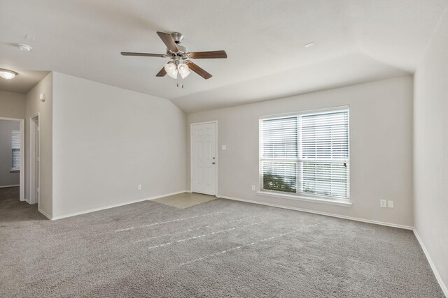 carpeted empty room with lofted ceiling, a ceiling fan, and baseboards