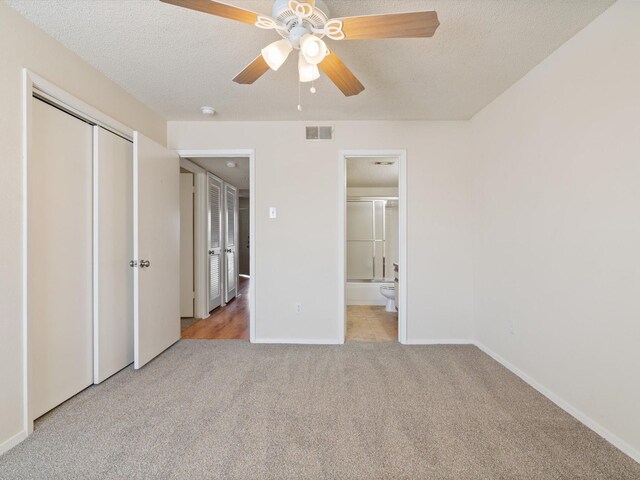 218 N Texas Blvd Unit 316, Denton, TX 76201 - unfurnished bedroom featuring visible vents, connected bathroom, baseboards, light carpet, and a textured ceiling