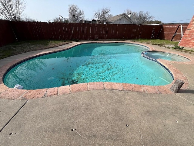 view of swimming pool featuring a fenced backyard and a pool with connected hot tub