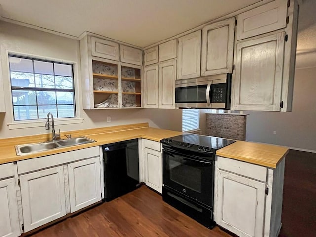 kitchen featuring dark wood finished floors, butcher block counters, white cabinets, black appliances, and a sink