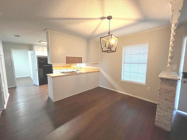 kitchen with a peninsula, refrigerator, dark wood-style flooring, a textured ceiling, and a chandelier