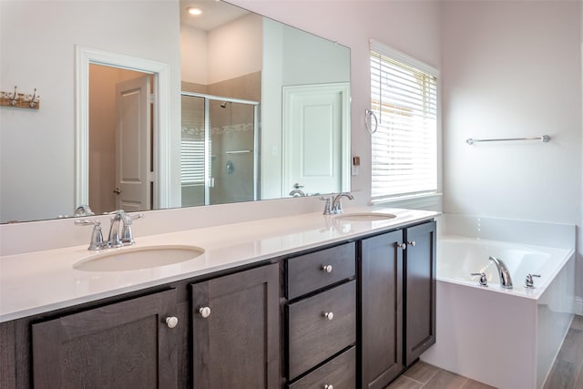 full bathroom with a sink, double vanity, a shower stall, and a garden tub