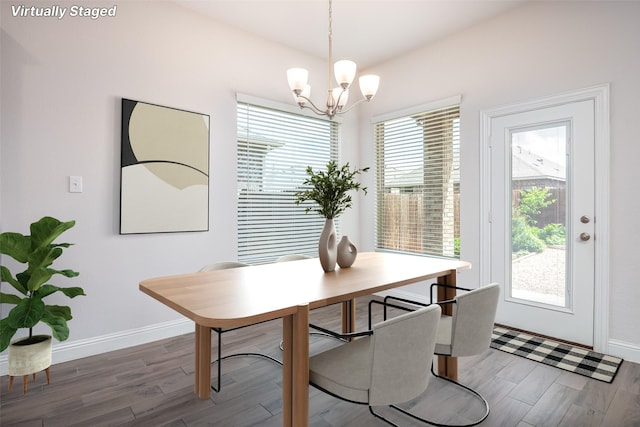 dining area featuring baseboards, wood finished floors, and a notable chandelier