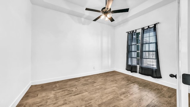 empty room featuring baseboards, wood finished floors, and ceiling fan