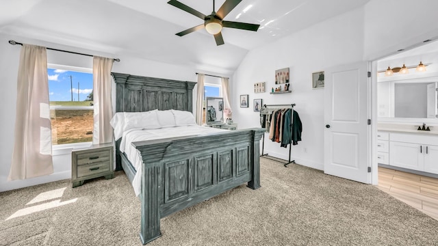 bedroom with ensuite bath, vaulted ceiling, ceiling fan, a sink, and baseboards