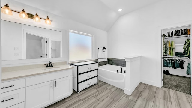 bathroom with recessed lighting, a bath, vaulted ceiling, and vanity