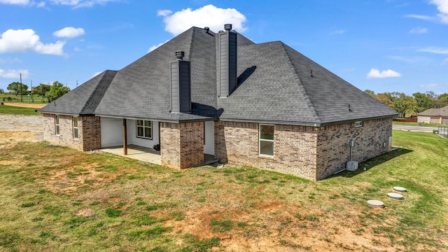 back of property with a chimney, a yard, a patio area, and brick siding