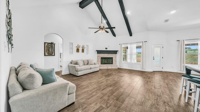 living room with beamed ceiling, high vaulted ceiling, a ceiling fan, arched walkways, and wood finished floors