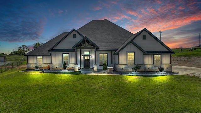 rear view of property with roof with shingles, stone siding, board and batten siding, and fence