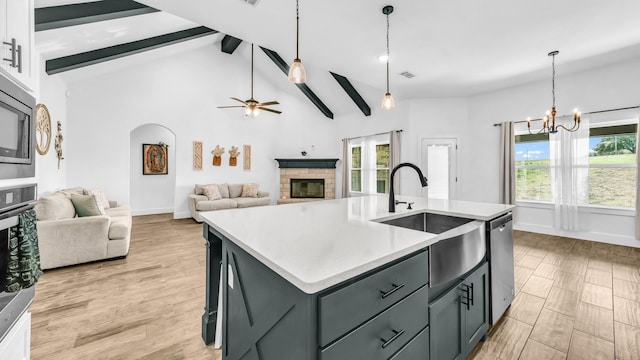 kitchen featuring beamed ceiling, a sink, a fireplace, light countertops, and appliances with stainless steel finishes