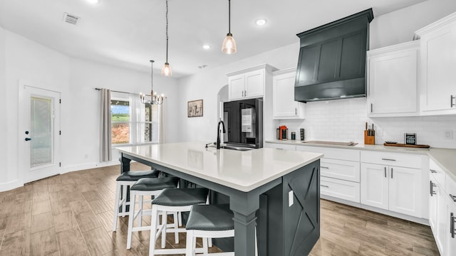 kitchen featuring backsplash, custom exhaust hood, light countertops, and a sink