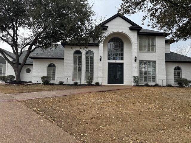 view of front facade with roof with shingles and brick siding