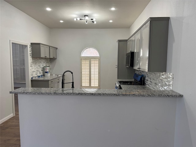 kitchen featuring light stone countertops, a sink, tasteful backsplash, stainless steel range with electric cooktop, and gray cabinetry