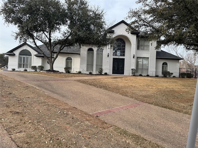view of front of house featuring roof with shingles, french doors, and brick siding