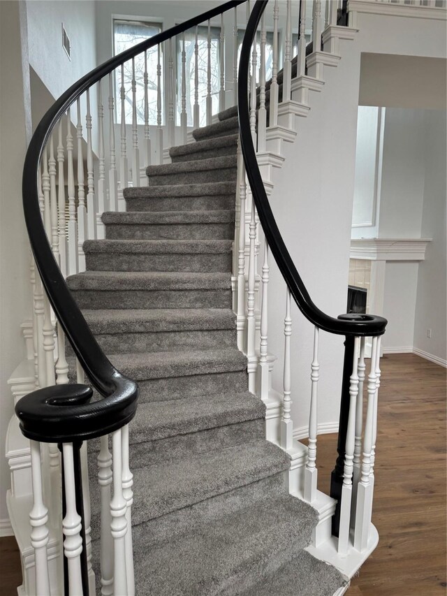 stairway with baseboards, visible vents, and wood finished floors
