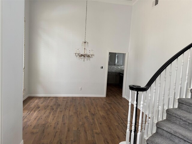 stairway featuring baseboards, visible vents, wood finished floors, and a notable chandelier