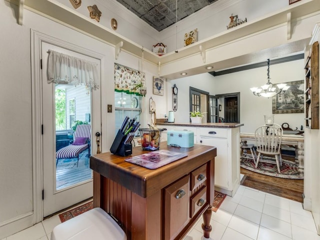 932 Williams St, Rockwall, TX 75087 - kitchen with a chandelier, light tile patterned floors, a peninsula, an ornate ceiling, and white cabinets