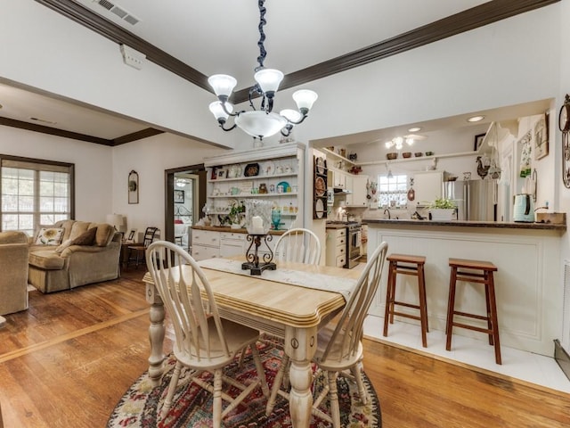 932 Williams St, Rockwall, TX 75087 - dining area with crown molding, a chandelier, light wood finished floors, and healthy amount of natural light