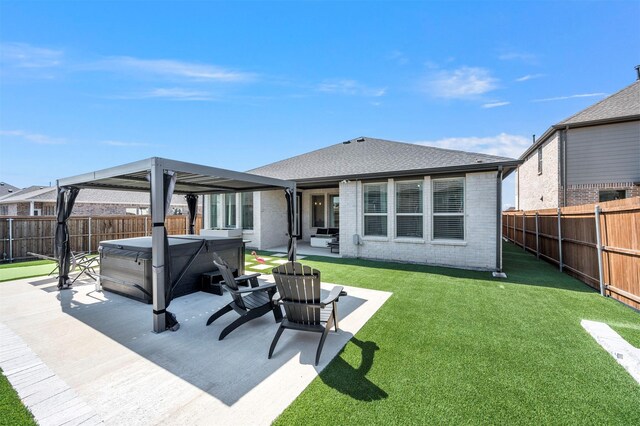 back of house featuring brick siding, a patio area, a hot tub, and a fenced backyard