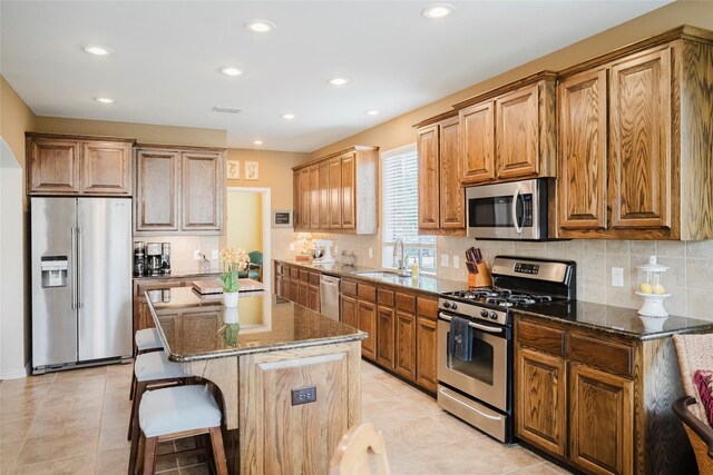 kitchen with recessed lighting, a sink, dark stone counters, and appliances with stainless steel finishes