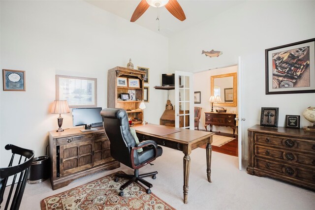 carpeted home office with a towering ceiling and ceiling fan