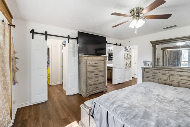 18341 Shore Dr, Kemp, TX 75143 - bedroom featuring ceiling fan, a barn door, baseboards, visible vents, and dark wood-style floors