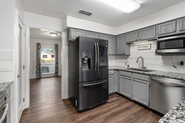 18341 Shore Dr, Kemp, TX 75143 - kitchen with a textured ceiling, visible vents, appliances with stainless steel finishes, gray cabinetry, and a sink