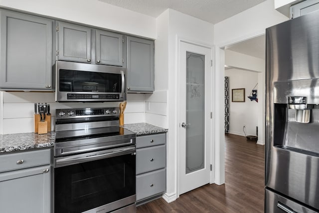 18341 Shore Dr, Kemp, TX 75143 - kitchen featuring gray cabinetry, appliances with stainless steel finishes, dark stone countertops, and dark wood-style flooring