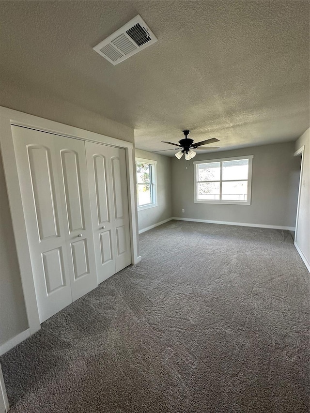 unfurnished bedroom featuring multiple windows, carpet, visible vents, and a closet