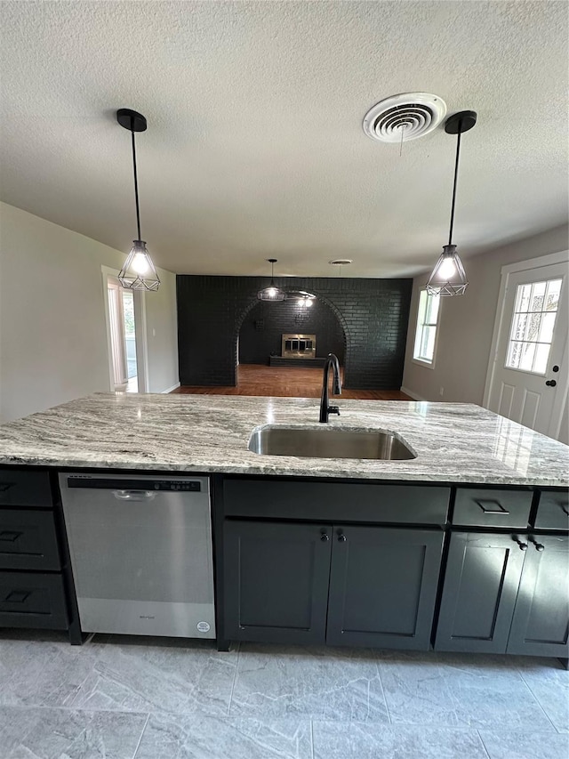 kitchen featuring light stone counters, a sink, visible vents, and stainless steel dishwasher