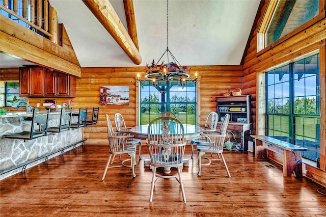 dining room with an inviting chandelier, beam ceiling, wood-type flooring, high vaulted ceiling, and log walls