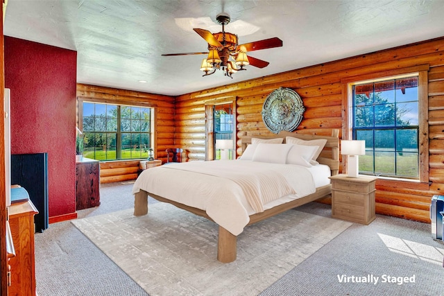 carpeted bedroom with a ceiling fan and rustic walls