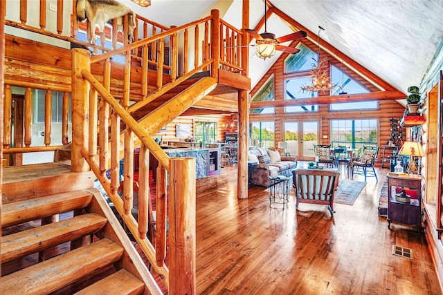living room with wood-type flooring, high vaulted ceiling, stairs, a ceiling fan, and visible vents