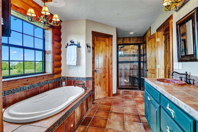 bathroom with a garden tub, tile patterned flooring, vanity, a shower stall, and a notable chandelier