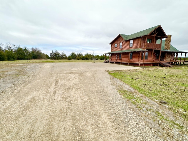 exterior space featuring dirt driveway, a wooden deck, and a chimney