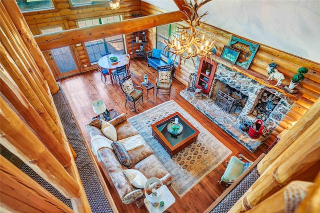 living room featuring an inviting chandelier, log walls, a wealth of natural light, and a fireplace