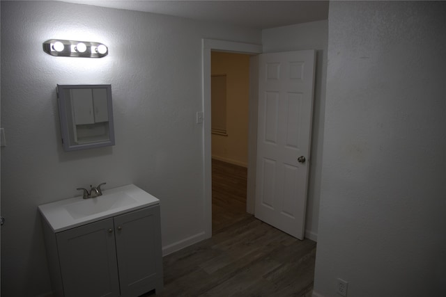 bathroom featuring baseboards, wood finished floors, and vanity