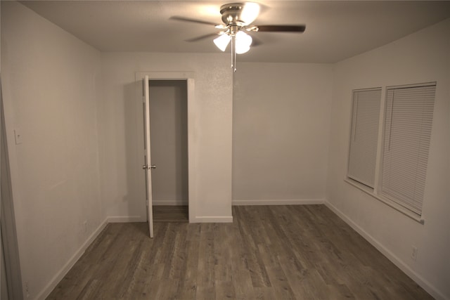 unfurnished bedroom with baseboards, a ceiling fan, and dark wood-type flooring
