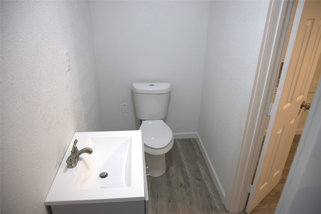 bathroom with baseboards, a textured wall, toilet, and wood finished floors