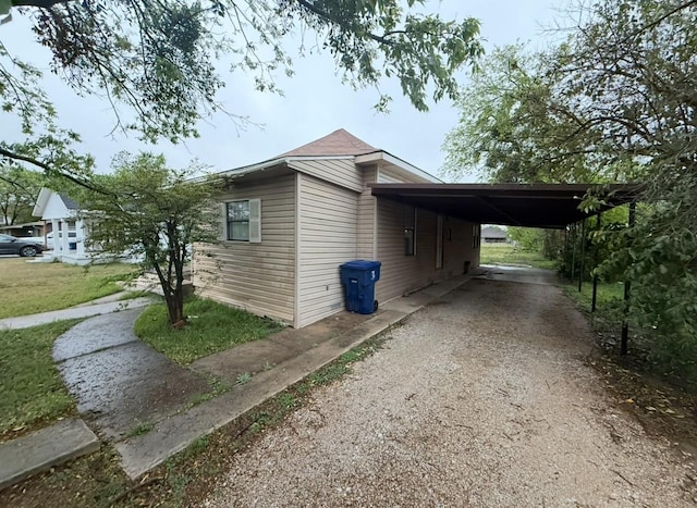 view of side of home featuring a carport and dirt driveway