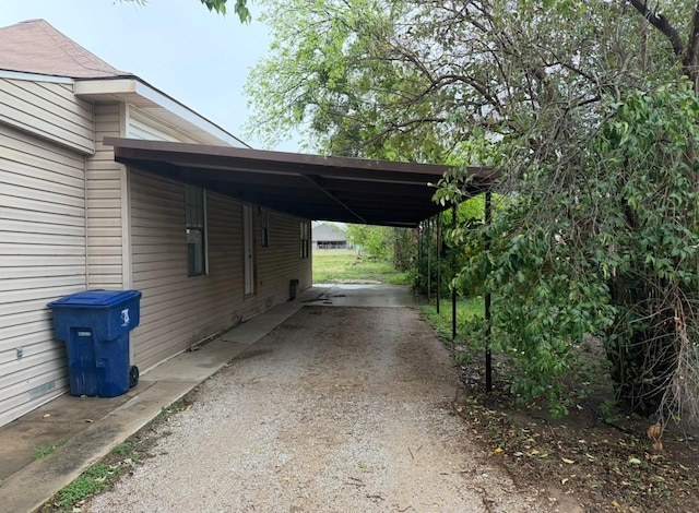 view of property exterior with dirt driveway and an attached carport