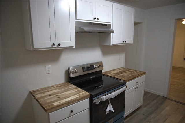 kitchen featuring dark wood finished floors, white cabinets, stainless steel electric stove, under cabinet range hood, and butcher block countertops