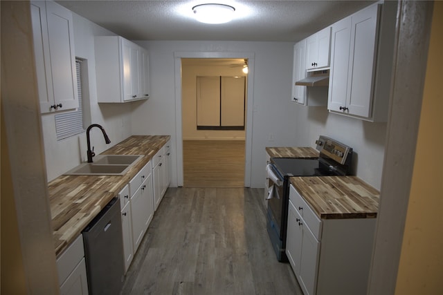 kitchen featuring a sink, butcher block counters, under cabinet range hood, electric stove, and dishwasher