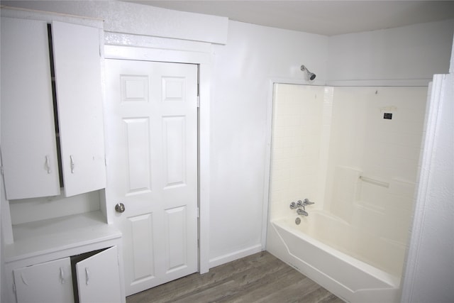 bathroom with baseboards, wood finished floors, and bathing tub / shower combination