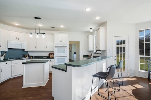 640 County Road 203, Collinsville, TX 76233 - kitchen featuring visible vents, white appliances, dark countertops, and dark wood finished floors