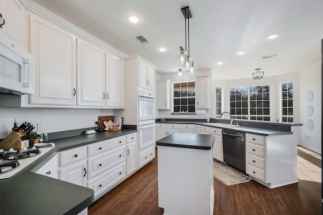 640 County Road 203, Collinsville, TX 76233 - kitchen with white appliances, dark countertops, a peninsula, and white cabinetry