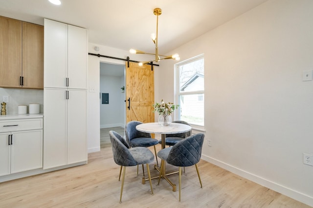 dining room with a barn door, baseboards, light wood finished floors, and a chandelier