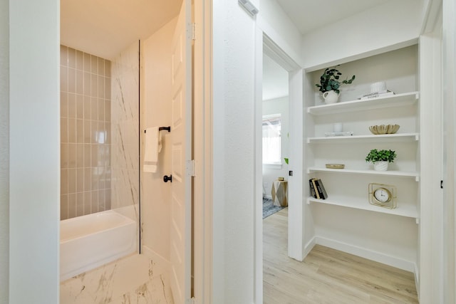 bathroom featuring shower / tub combination, wood finished floors, and baseboards