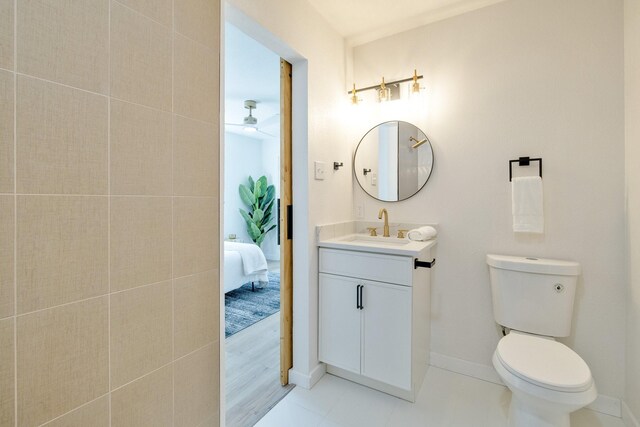 ensuite bathroom with tile patterned floors, toilet, connected bathroom, baseboards, and vanity