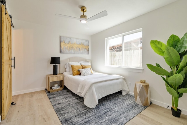 bedroom featuring light wood-style flooring, baseboards, and a barn door
